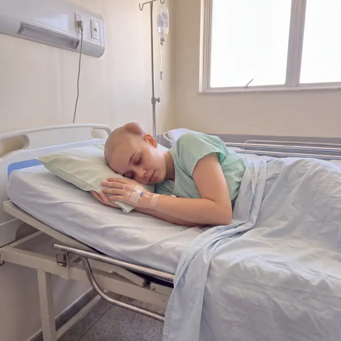 Ela deitada na cama do hospital, de cabeça raspada e com o soro na mão